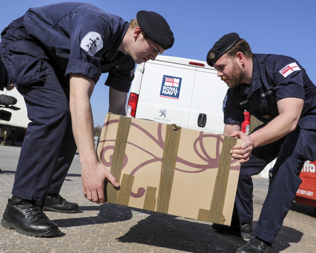 Royal Navy sailors lift a box