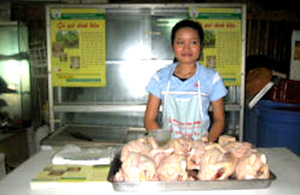 A vendor sells certified chickens in a Vietnamese market.