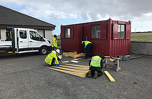 Workers installing a welfare cabin at a local medical practice