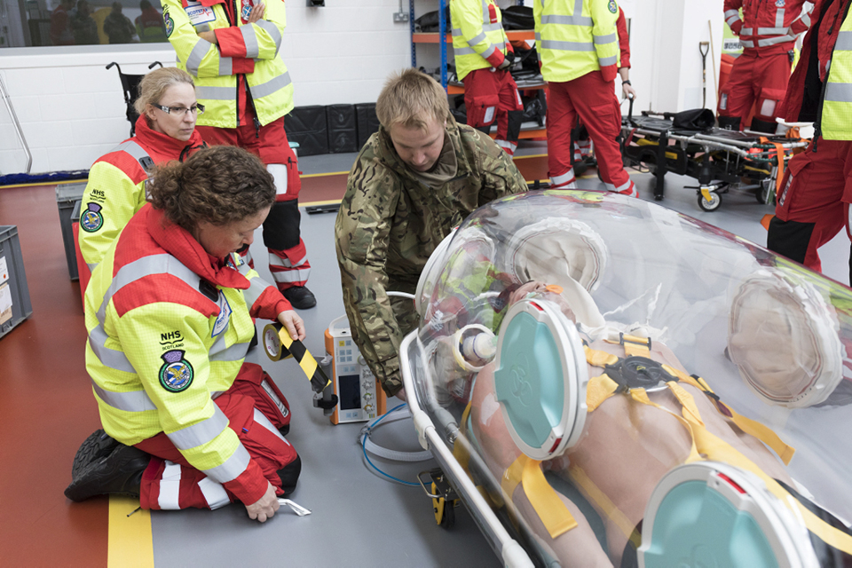 A team of doctors and a member of the RAF group round specialist air transfer equipment. 