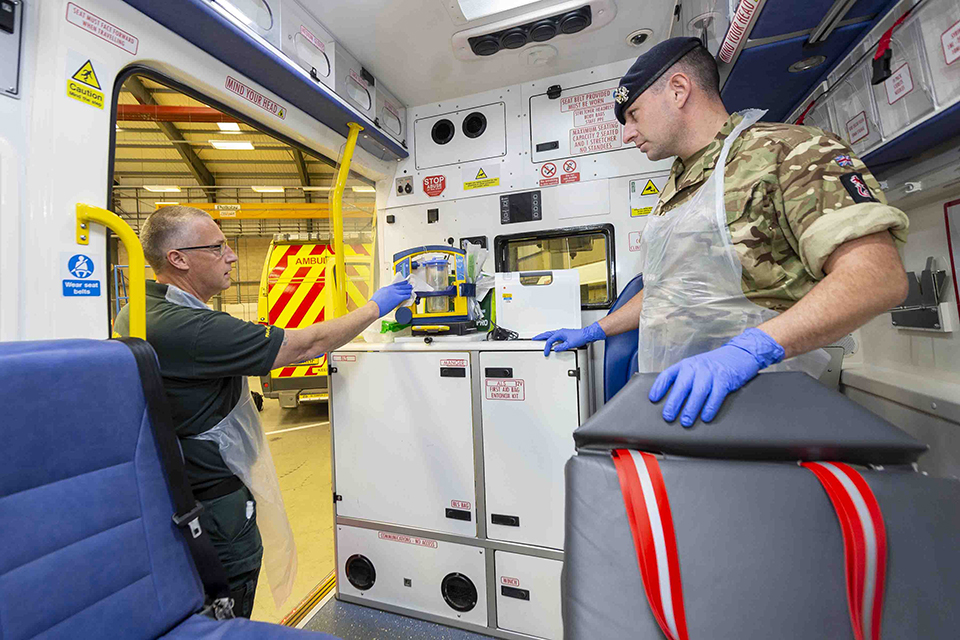 A paramedic and a soldier in the back of an ambulance. 
