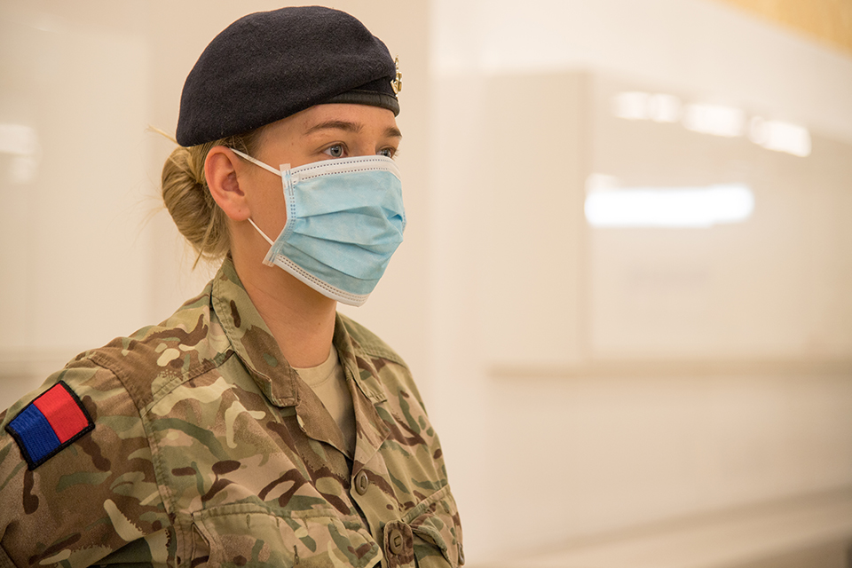 A female soldier wears a PPE face mask