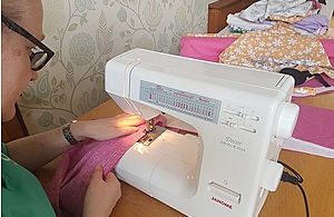 Sellafield Ltd employee sitting sewing PPE as a volunteer