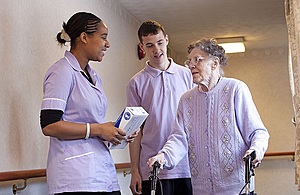 Two carers with elderly woman in care home