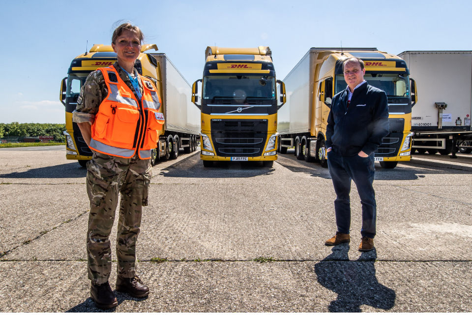 Squadron Leader Donna Rogerson standing in front of 3 HGV haulage lorries. 