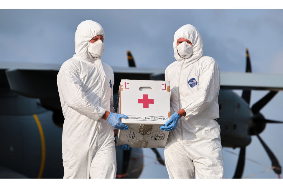 Medical supplies being carried by two individuals dressed in PPE. 