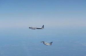 Two planes - one Russian and one RAF Typhoon - fly against a blue sky