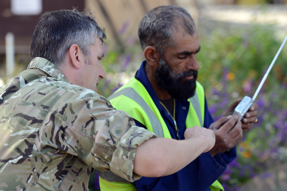 Lieutenant Jo Nicholson and an Afghan man listen to a portable radio