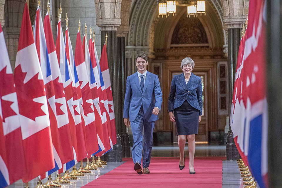 PM Theresa May and Canadian PM Justin Trudeau walking along UK/Canadian flags