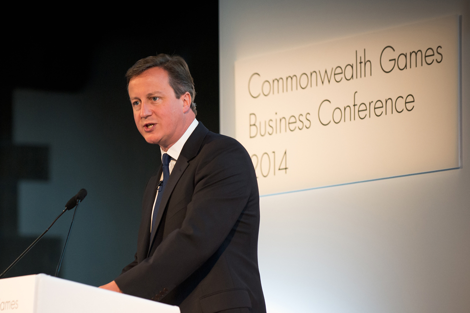 David Cameron speaking from a podium at the Commonwealth Games Business Conference.
