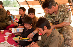 Warrant Officer Taff Davies helps Afghan children with their reading skills