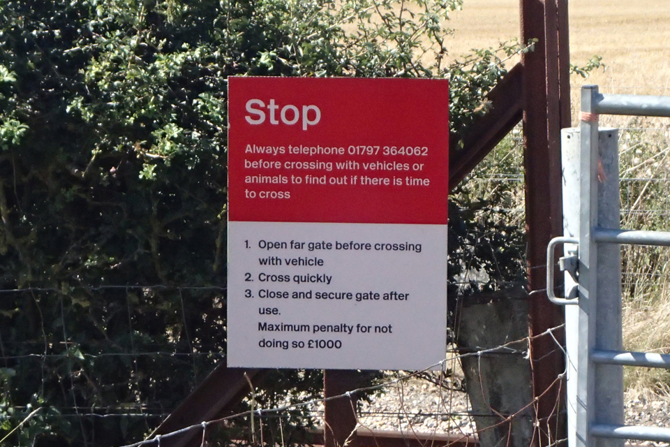 One of the red and white signs displayed on either side of the crossing. This tells crossing users to stop and phone the signaller if they need to move animals or vehicles across the crossing and explains what actions they need to take..