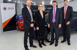 Greg Clark and representatives from the automotive sector standing in front of the car.