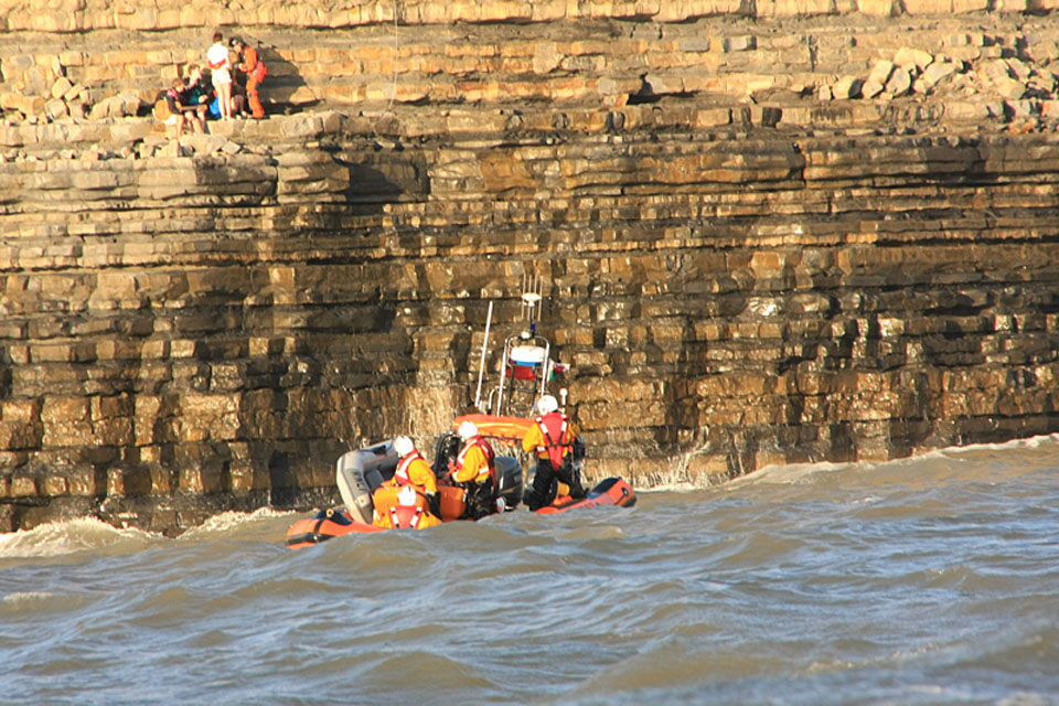 Sergeant Rachel Robinson prepares to lift the teenagers to safety as a lifeboat crew looks on from the sea below