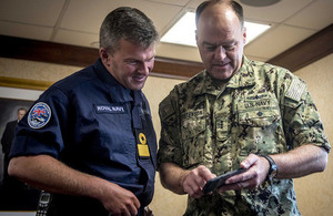 Strike Group Commander Cdre. Andrew Betton, left, looks at photos with Vice Adm. John Christenson, U.S. Military Representative to NATO, aboard the aircraft carrier USS George H.W. Bush.