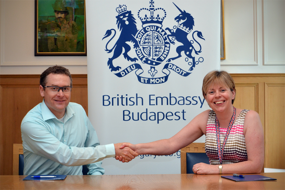 Deputy Head of Mission Theresa Bubbear signing a support contract with Ervin Bonecz, managing director of 90 decibel Project