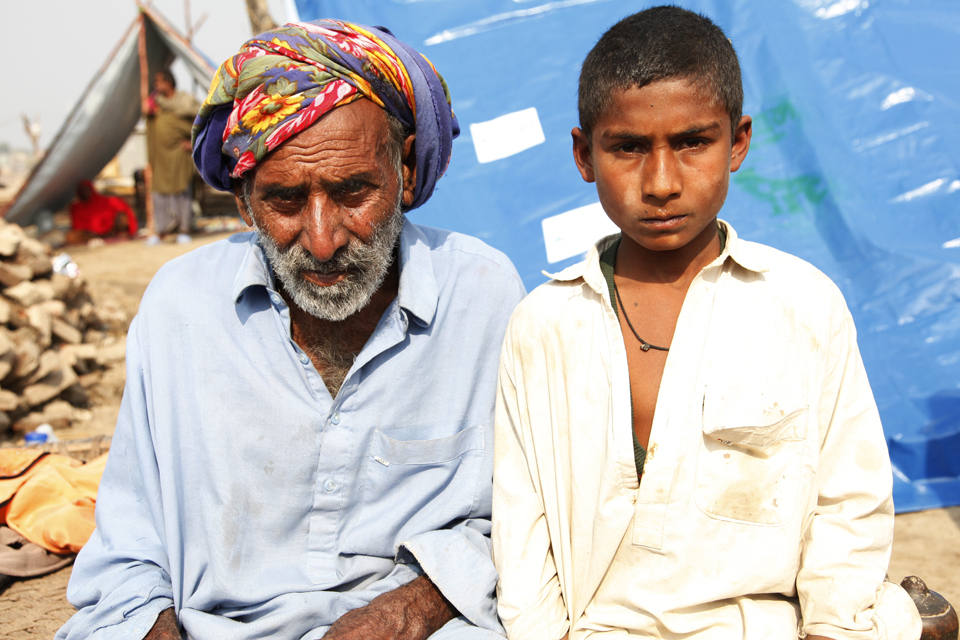 Waseem and his grandfather in front of a temporary shelter made from heavy-duty plastic sheeting. Picture: Russell Watkins/DFID