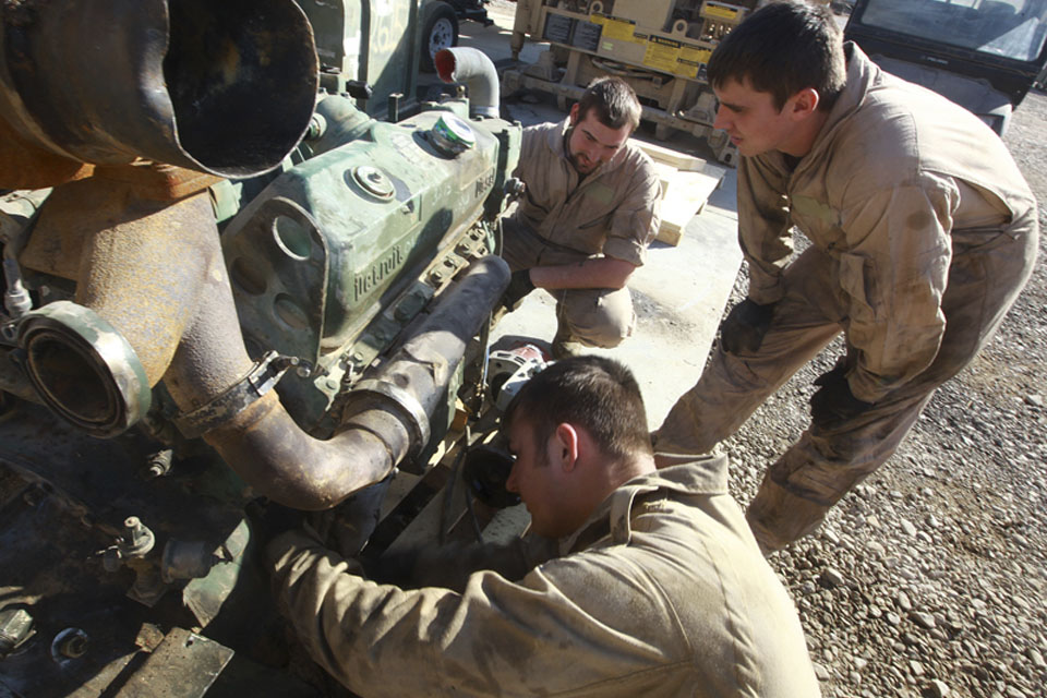 Craftsman Adam Evans (foreground) and Lance Corporal Craig Heaton (right) troubleshoot a Detroit Diesel V6 Logistics Vehicle System truck engine at the Intermediate Maintenance Activity lot in Camp Leatherneck 