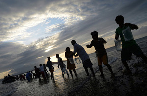 People form a chain to unload water and shelters from HMS Daring's sea boat off the island of Tulunanaun [Picture: Leading Airman (Photographer) Keith Morgan, Crown copyright]