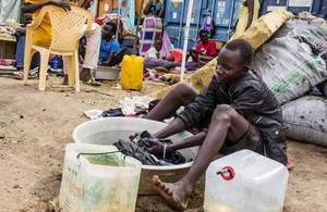 A teenager displaced by violence washes clothes in a basin in South Sudan, January 2014. Picture: K McKinsey/UNCHR