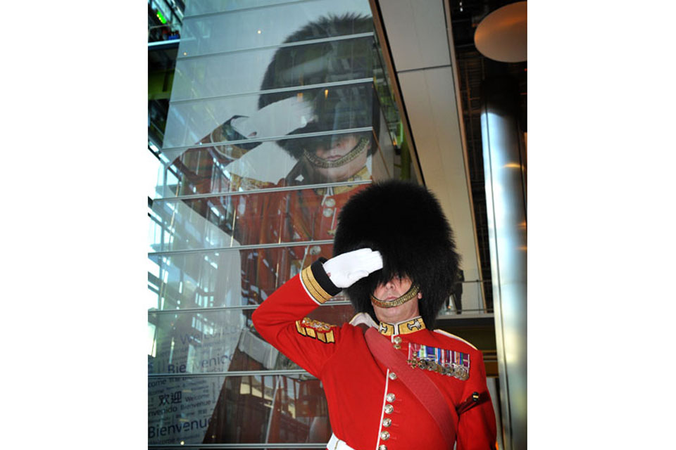 The Garrison Sergeant Major of London District William Mott in front of the picture of himself at London Heathrow's Terminal 5 