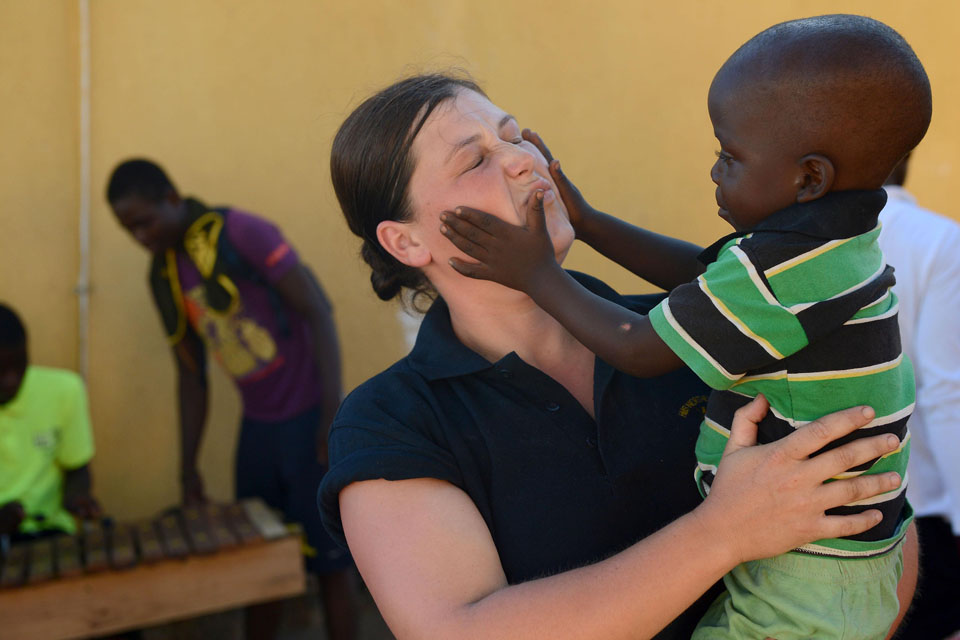 A young boy squeezes a sailor's face