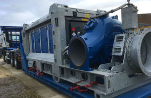 Large blue-and-silver pump in foreground, loaded on the back of a lorry