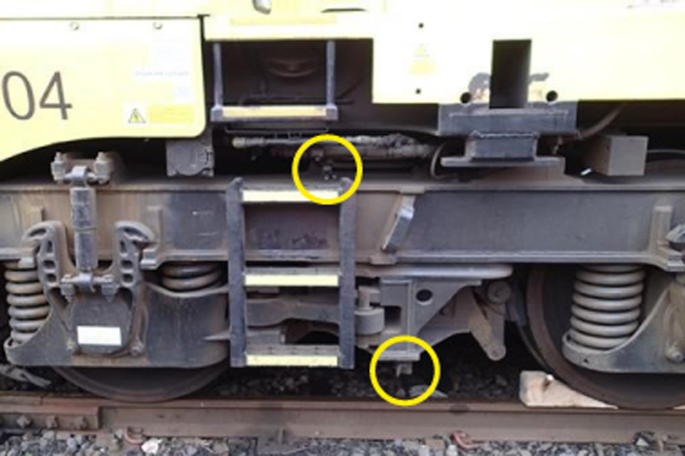View of the locomotive's bogie. The parking brake isolation handle at the bottom of the bogie is highlighted with a yellow circle. The bogie brake isolation valve is at the centre top of the bogie, highlighted with a yellow circle.
