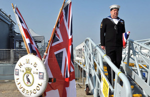 Able Seaman Anthony Clarke carries HMS Liverpool's folded White Ensign under his arm on the gangway