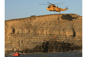 An RAF Sea King Search and Rescue helicopter lowers winchman Sergeant Rachel Robinson down the rock face at Dunraven Bay to reach the stranded teenagers