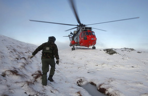 A serviceman approaches HMS Gannet's Search and Rescue helicopter