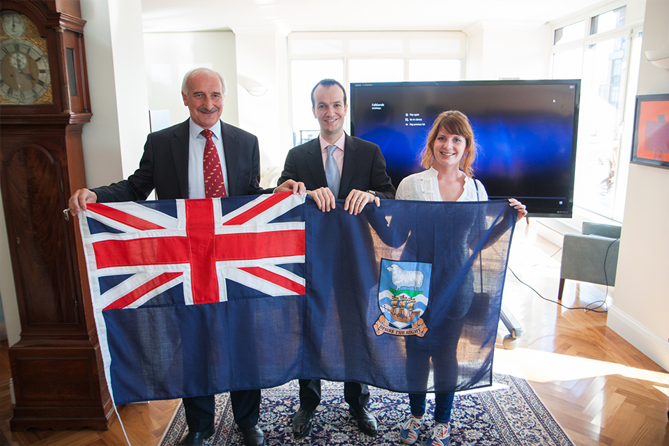 Mike Summers, Danny Lopez, and Teslyn Barkman hold the Falkland Islands flag.