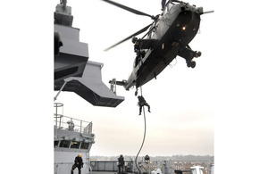 Royal Marines demonstrate a fast-rope attack from a Sea King helicopter onto the starboard bridge wing of HMS Bulwark