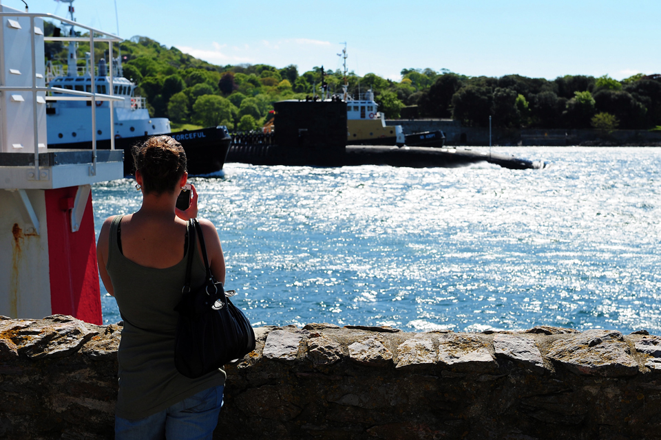 A woman watches HMS Trenchant return to Devonport