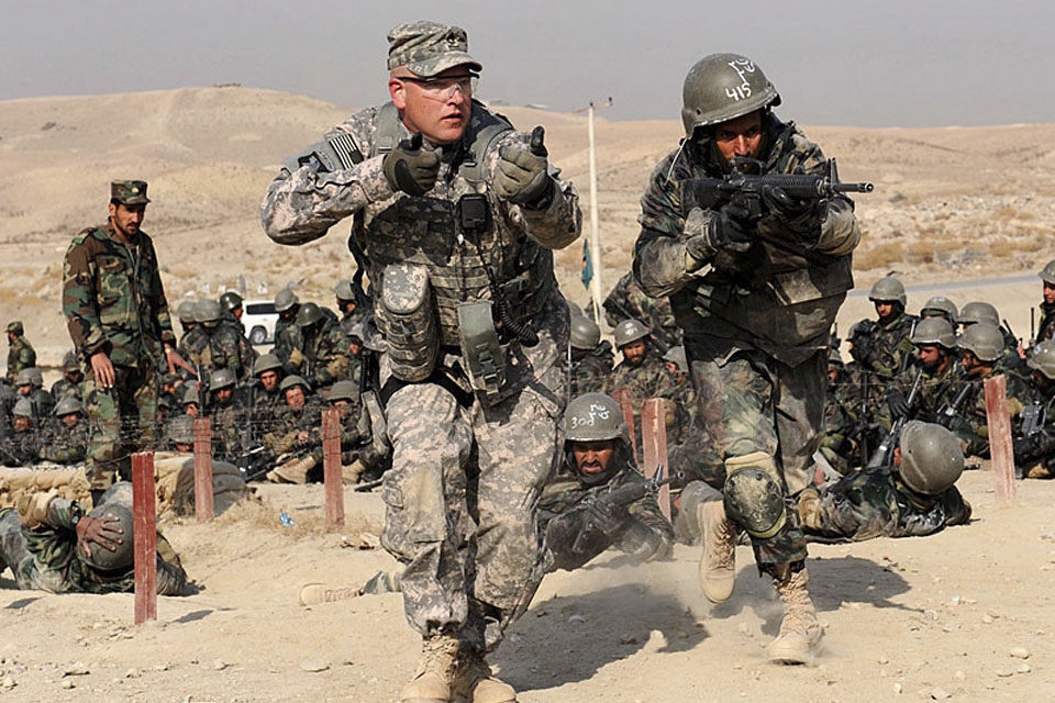 A United States Army mentor mirrors an Afghan National Army trainee for technique corrections during a field training exercise at the Kabul Military Training Centre