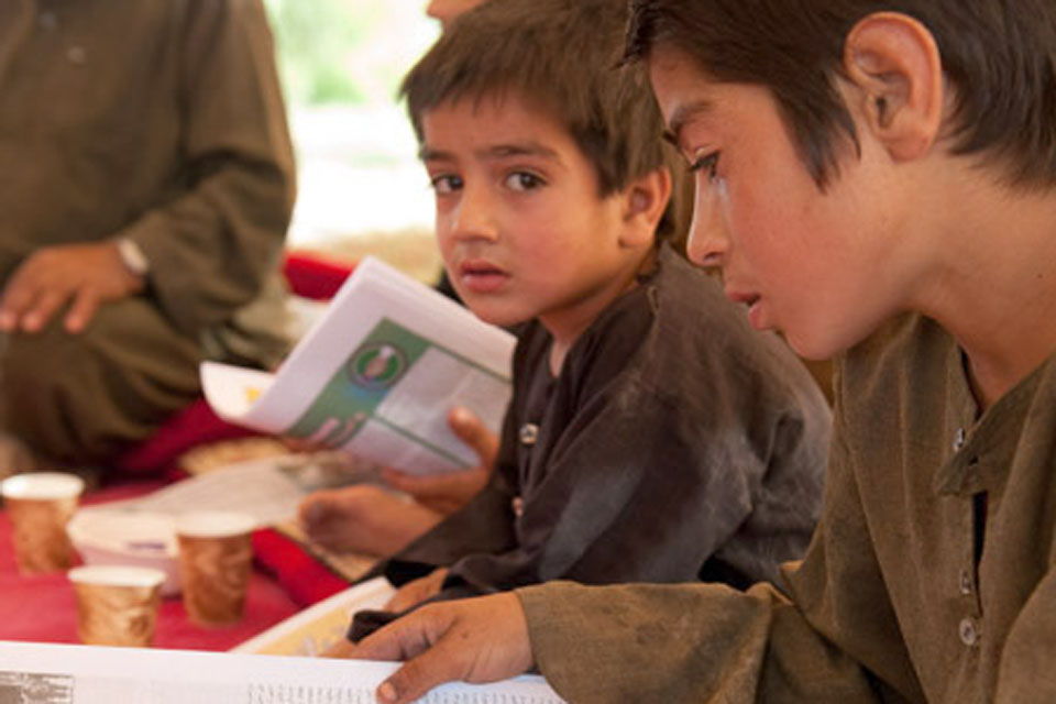 Afghan children using ISAF newspapers printed in Dari, Pashtu and English to improve their reading skills