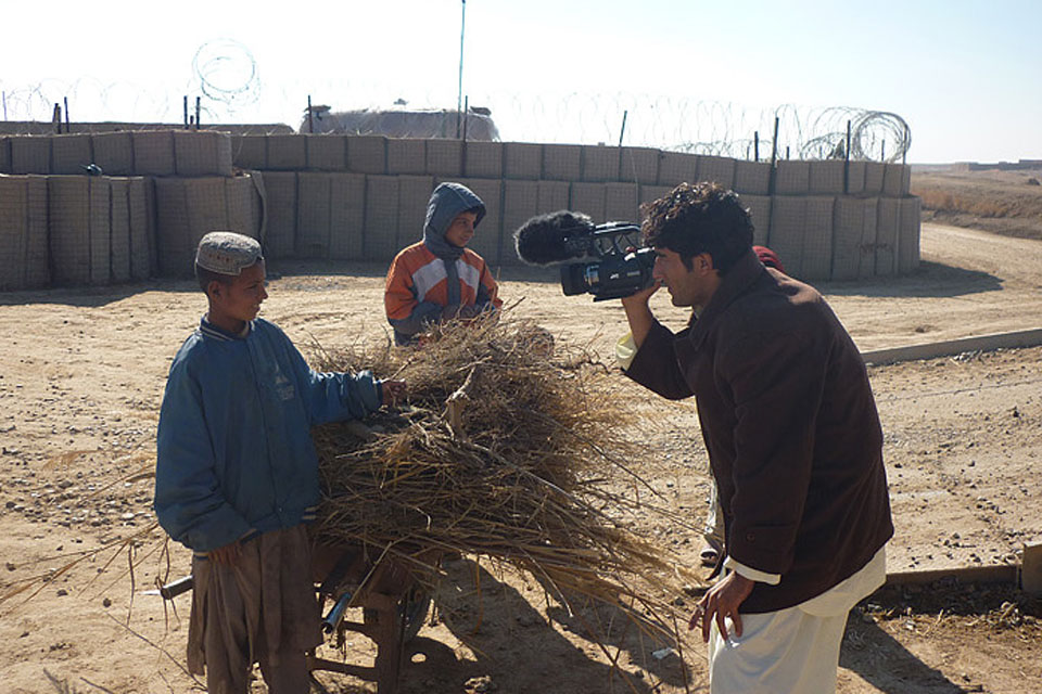An Afghan cameraman films two local boys outside an ISAF patrol base