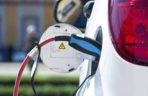 Close-up of charging cable into rear of white electric car