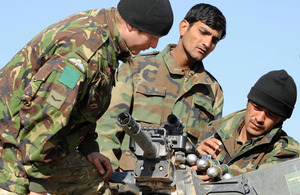 Lance Corporal Wiltshire shows Afghan warriors how to operate a grenade machine gun