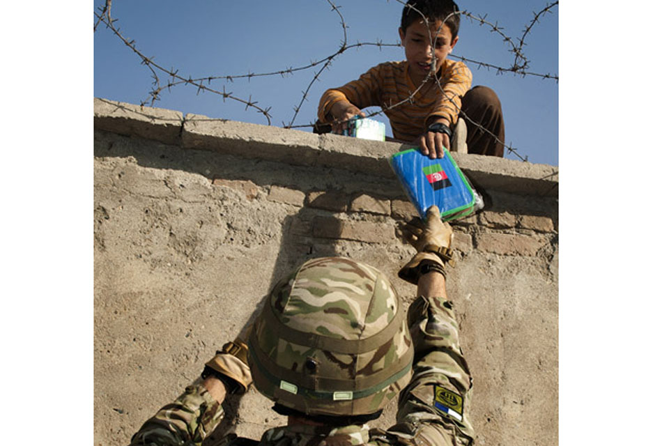 Major Kev Read of 16 Signal Regiment hands a pencil case to a child