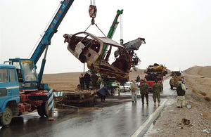 Afghan contractor clears the rusting hulks of abandoned vehicles from Highway 1, east of Lashkar Gah, Helmand province