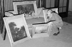 Captain H H Davies of Birkenhead, checks a collection of paintings found in the house of a member of the SS in Hanover in 1945