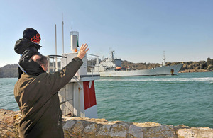 A man carrying a young boy waves from the shore as HMS Scott returns to Plymouth [Picture: Leading Airman (Photographer) Caroline Davies, Crown copyright]