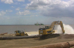 Diggers on the beach distributing sand pumped from licensed off-shore sites