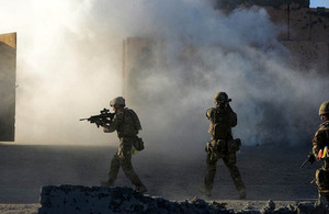 Royal Marines commandos mount an attack on an enemy village using cover from a smoke grenade [Picture: Petty Officer (Photographer) Sean Clee, Crown copyright]