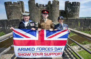 Navy, Army and RAF personnel holding Armed Forces Day flag