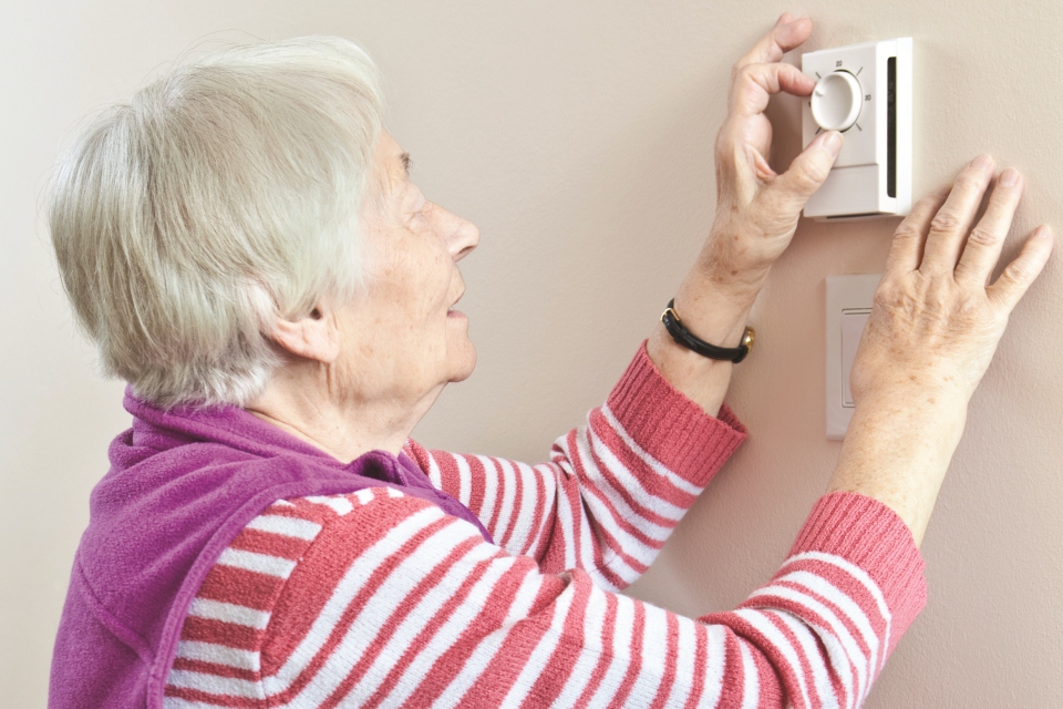Lady reaching for her heating thermostat