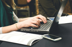 Woman at laptop with smartphone