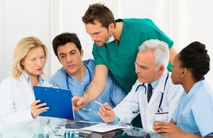 team of medical staff around a table looking at medical charts