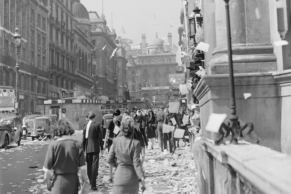 Civilians walk amongst the piles of torn up paper which have been thrown, 'ticker tape'-style, from the windows of offices, on Lower Regent Street, London, to celebrate the signing of the Peace with Japan.